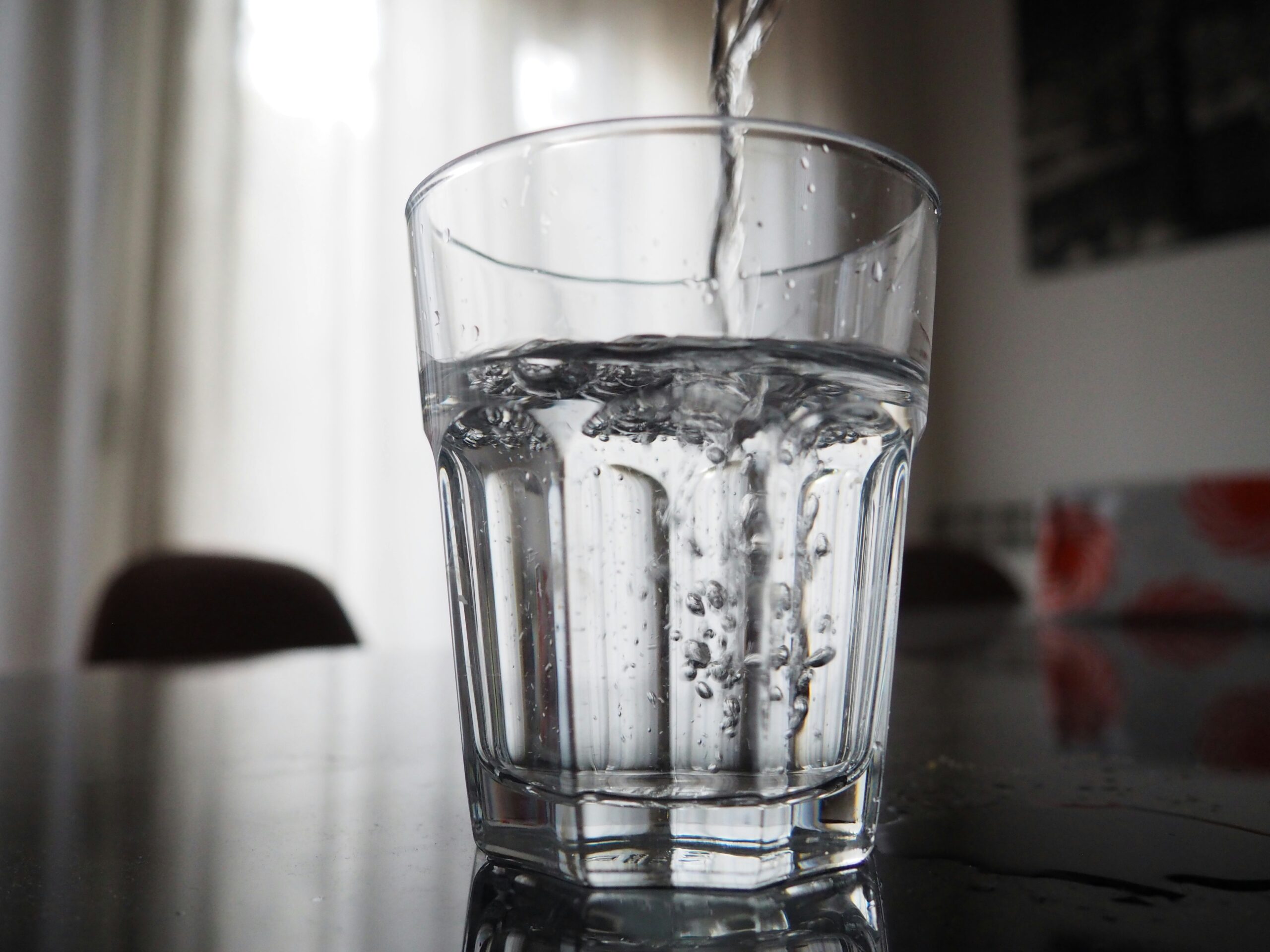Glas mit frischem Wasser auf sauberem Untergrund